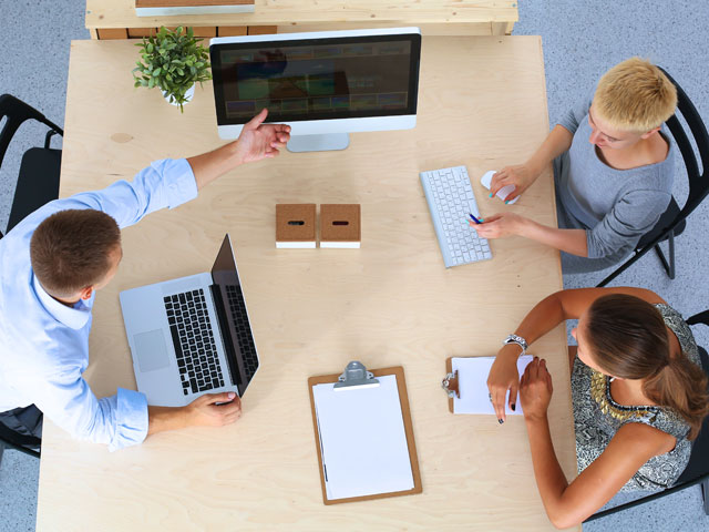 Coworkers at a conference table looking at a computer.