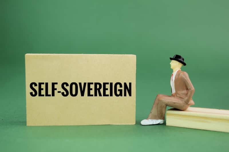 Image showing a model of a person sitting next to a sign that reads self sovereign