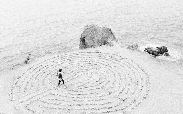 Aerial view of a woman walking in a shell maze on a beach